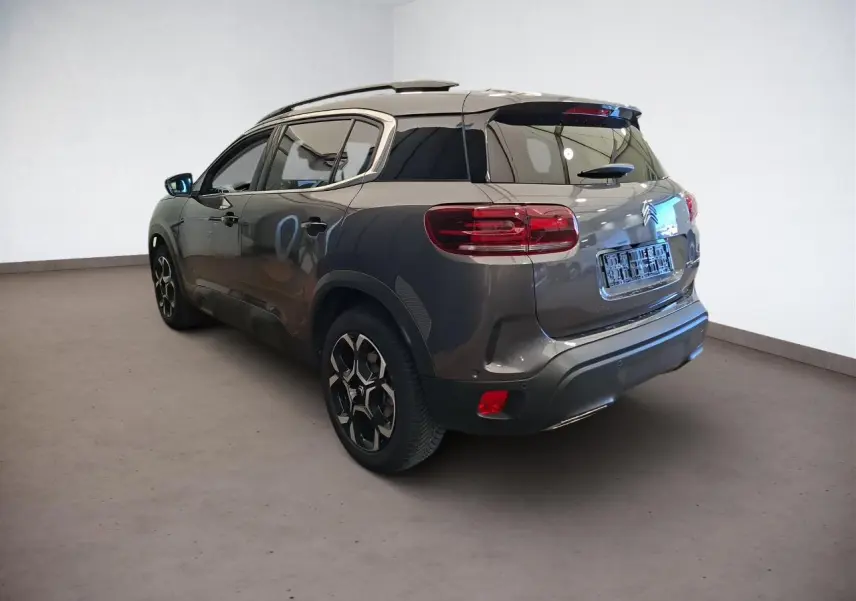 Vue 3/4 arrière droit d'un Citroën C5 Aircross gris Platinium avec jantes alliage et vitres teintées.