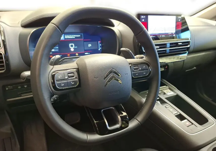 Vue intérieure centrée sur le volant cuir noir et le tableau de bord numérique du Citroën C5 Aircross 2025.