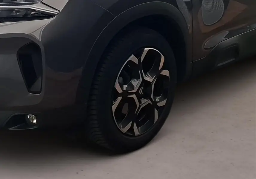Gros plan sur la roue avant gauche et partie basse avant du Citroën C5 Aircross gris Platinium avec jante alliage 18'' bi-ton.