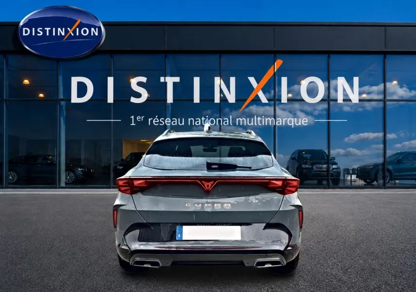 Vue arrière d'un CUPRA Formentor bleu fjord 2026 avec feux LED et double sortie d'échappement, devant un showroom Distinxion.