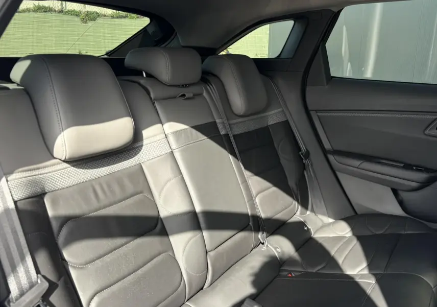 Vue intérieure arrière droite des sièges en cuir noir du Citroën C5 X 2024, avec appuie-têtes et ceintures visibles.