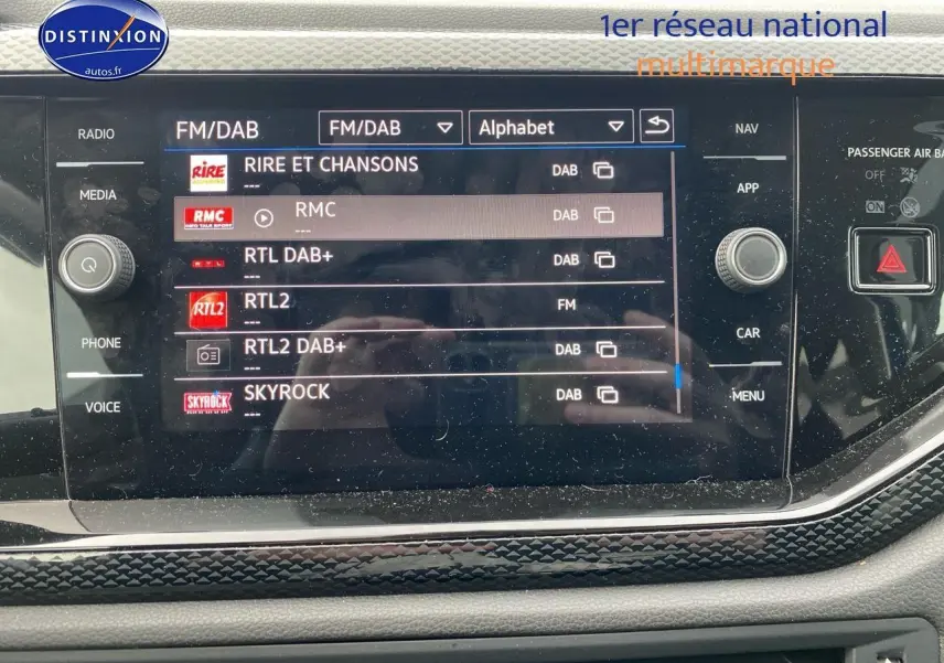 Écran tactile central de la Volkswagen Polo 2025 affichant les stations radio DAB, entouré de commandes noires brillantes.