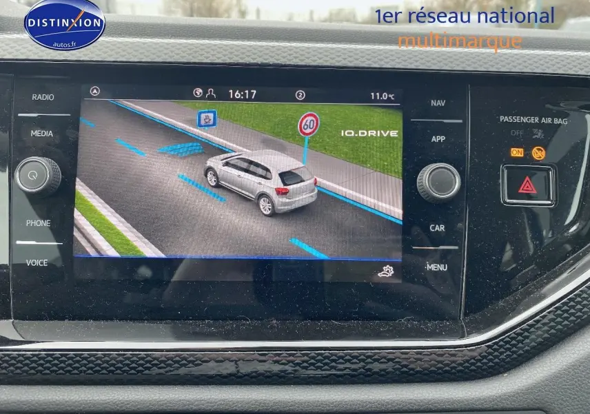 Écran de navigation affichant une Volkswagen Polo blanche vue de 3/4 arrière sur route avec limite à 60 km/h.