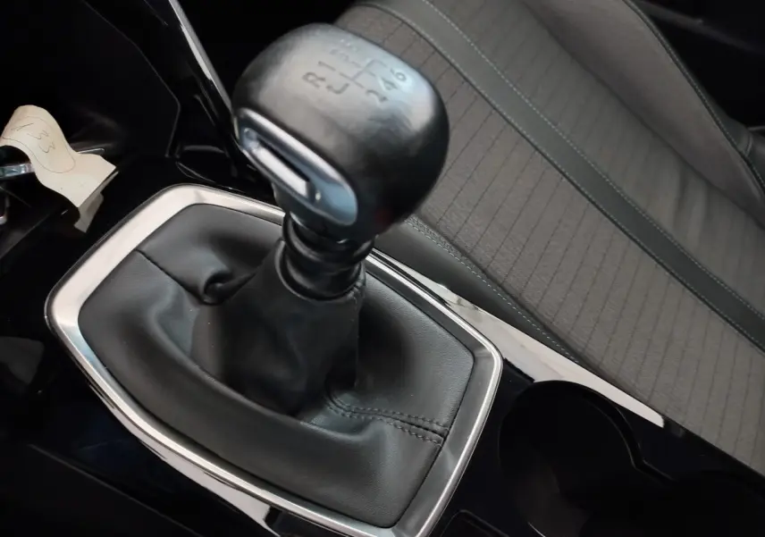 Gros plan sur le levier de vitesses manuel noir et la sellerie grise à motifs de la Peugeot 208 PureTech 100 S&S Allure.