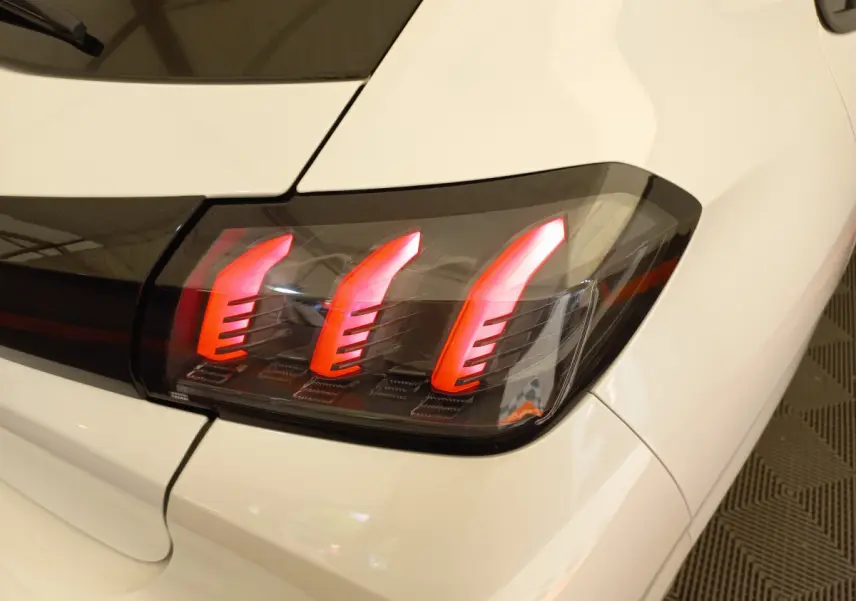 Gros plan sur le feu arrière droit rouge du Peugeot 208 blanc, soulignant son design moderne et distinctif.