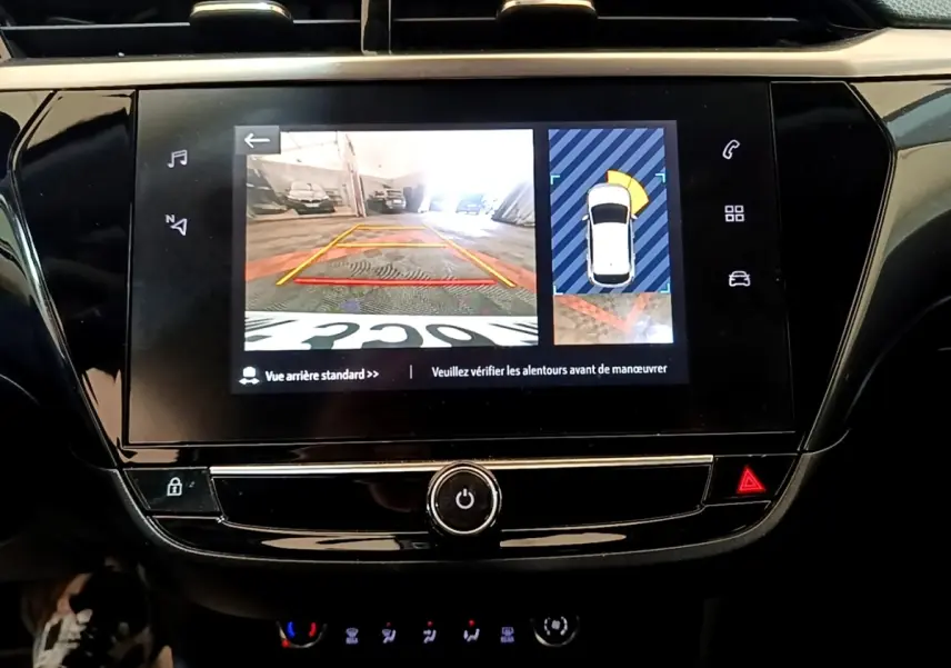 Écran tactile central de la console de l’Opel Corsa blanc 2023 montrant la caméra de recul et l’aide au stationnement.