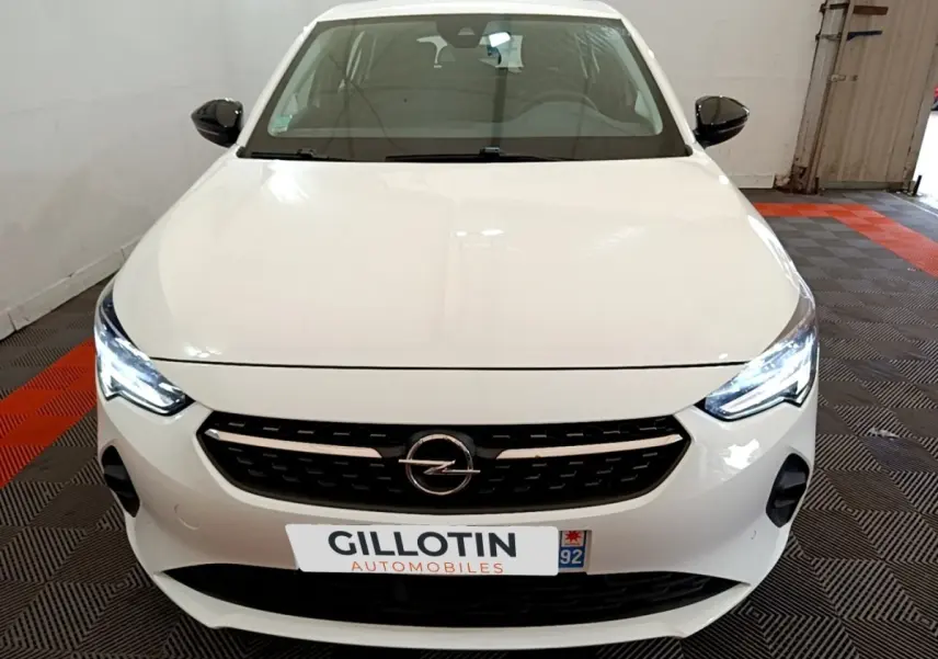 Vue avant d'une Opel Corsa blanche 2023 avec phares LED allumés et calandre noire distinctive.