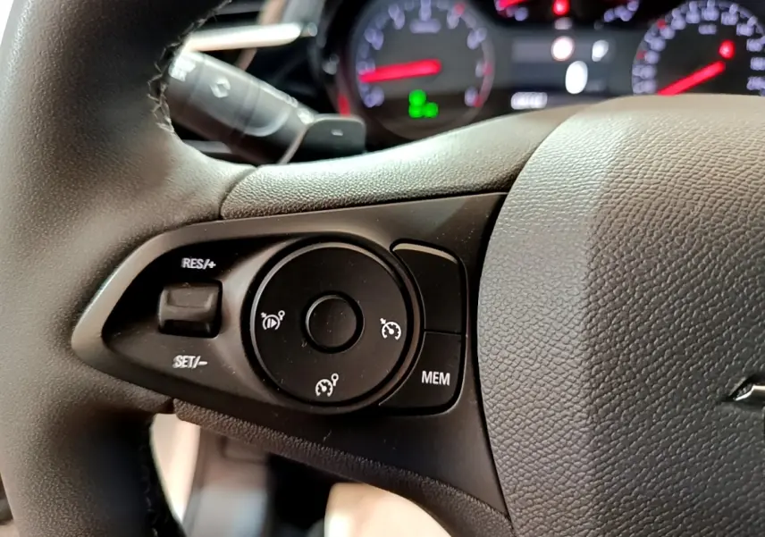 Gros plan sur le volant cuir noir de l’Opel Corsa 2023, avec commandes de régulateur de vitesse visibles.