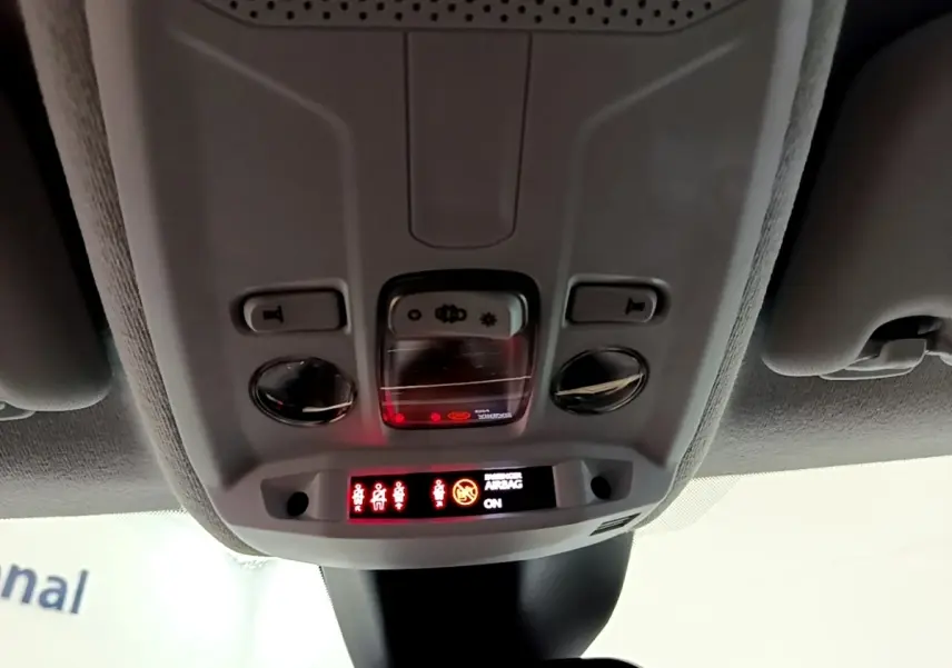 Vue intérieure du plafonnier avant de l’Opel Corsa blanc, avec commandes d’éclairage et affichage airbag actif.
