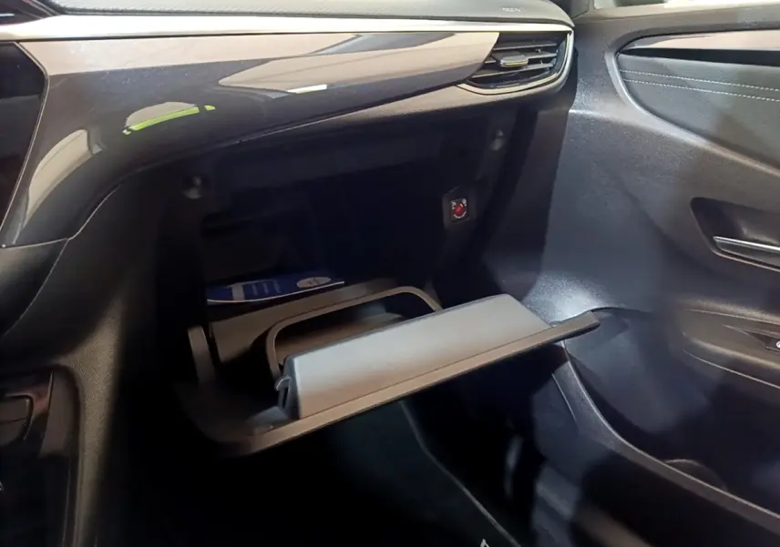 Vue intérieure côté passager de la boîte à gants ouverte de l’Opel Corsa blanche 2023 avec tableau de bord noir brillant.