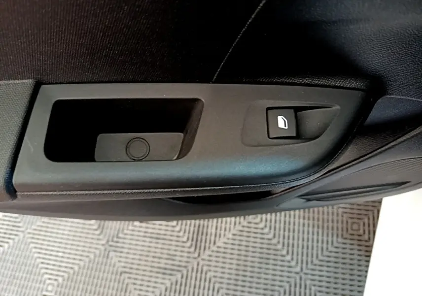 Gros plan sur la commande de lève-vitre électrique côté porte intérieure d'une Opel Corsa blanche de 2023.