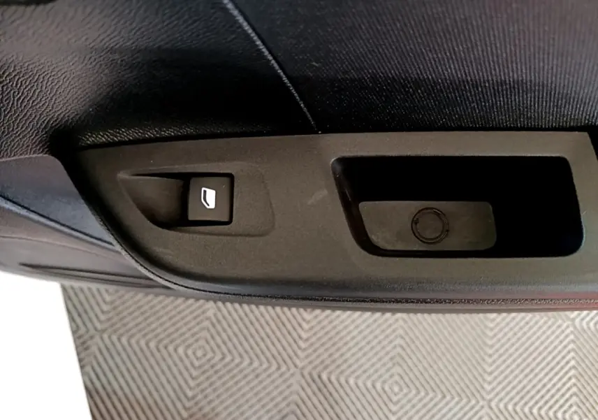 Détail de la commande de lève-vitre sur la porte intérieure côté conducteur d’une Opel Corsa blanche 2023.