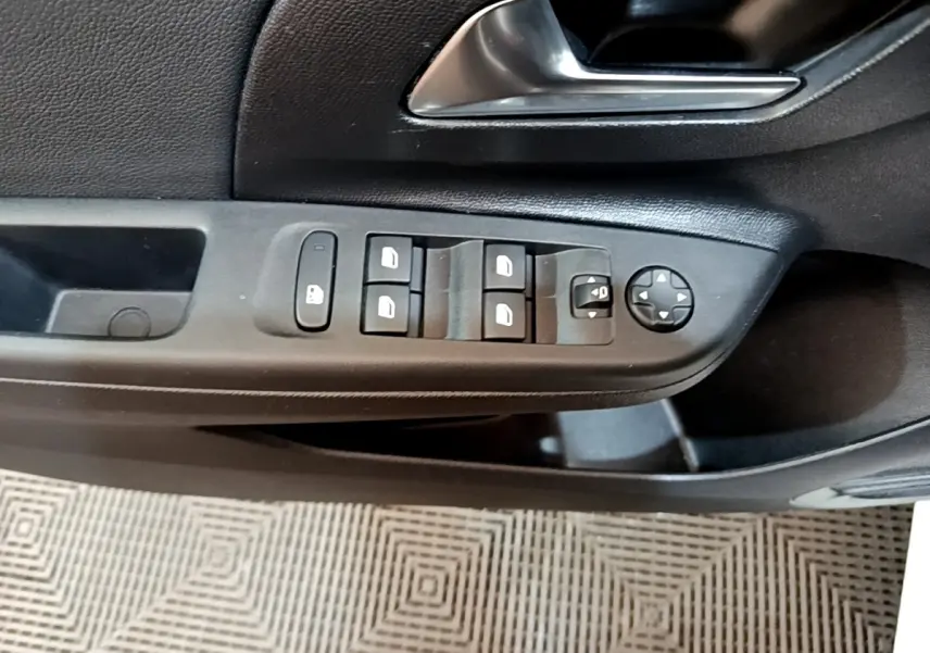 Vue rapprochée de la porte côté conducteur de l’Opel Corsa blanche, avec commandes électriques des vitres et rétroviseurs.