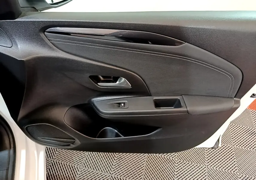 Vue rapprochée de la porte avant gauche noire de l’Opel Corsa blanche 2023, avec poignée et commande de vitre électrique.
