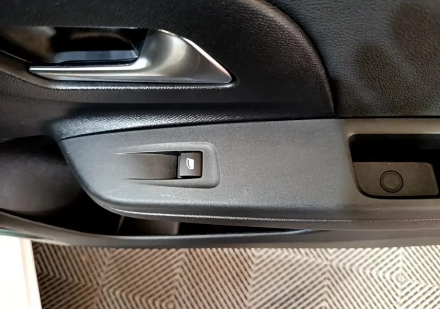 Détail de la porte côté gauche de l’Opel Corsa blanche 2023, avec poignée argentée et bouton de lève-vitre.