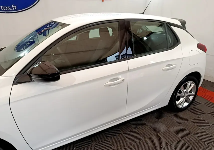 Vue de profil côté gauche d’une Opel Corsa blanche 2023 avec rétroviseurs noirs et jantes alliage.