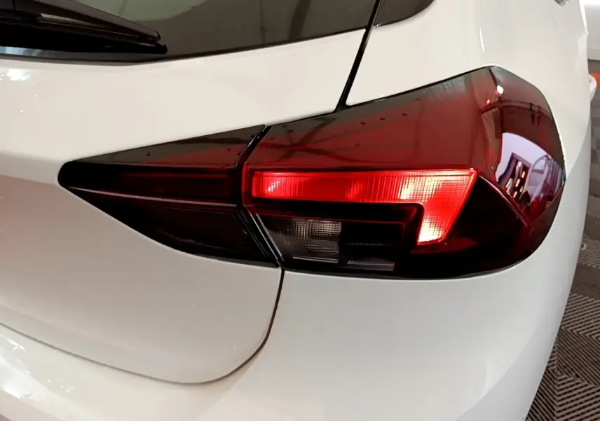 Gros plan sur le feu arrière droit rouge et noir de l’Opel Corsa blanche, vue arrière côté droit.