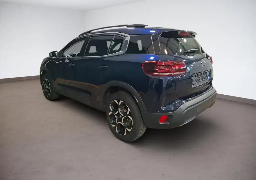 Vue 3/4 arrière droit du Citroën C5 Aircross Bleu Eclipse avec jantes alliage et barres de toit noires.