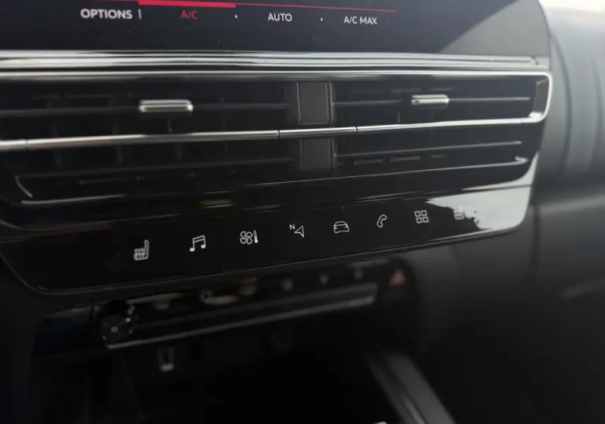 Vue rapprochée de la console centrale noire brillante du Citroën C5 Aircross 2025 avec commandes tactiles et aérateurs horizontaux.
