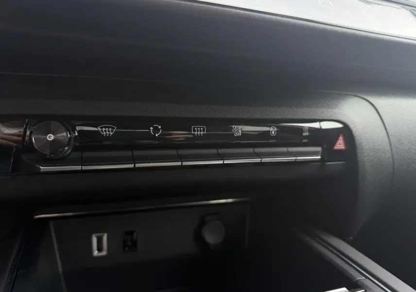 Vue rapprochée de la console centrale noire du Citroën C5 Aircross 2025 avec commandes climatisation et prise USB visible.
