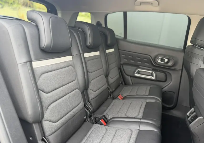 Vue latérale droite des trois sièges arrière indépendants gris et noirs du Citroën C5 Aircross 2025, avec appuis-tête et ceintures visibles.