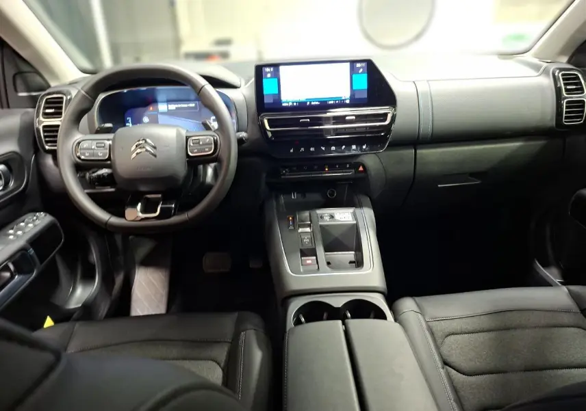 Vue intérieure avant de la Citroën C5 Aircross 2025, tableau de bord noir avec écran tactile et volant multifonction.