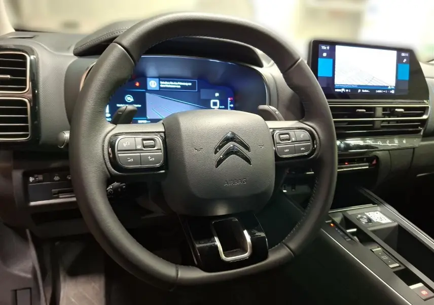 Vue rapprochée du volant cuir noir et du combiné numérique du tableau de bord du Citroën C5 Aircross 2025.