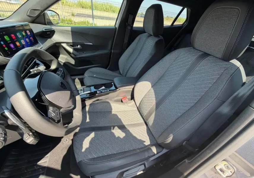 Intérieur gris du Peugeot 2008 Hybrid 145 Allure 2025, vue côté conducteur avec sièges tissu et tableau de bord digital.