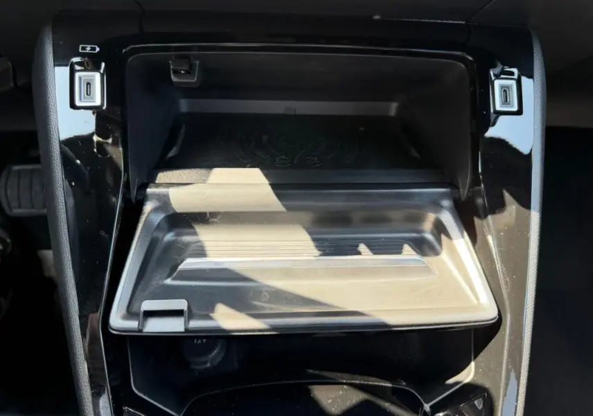 Gros plan sur la console centrale noire du Peugeot 2008 Hybrid 145 e-DCS6 Allure 2025 avec compartiment ouvert et ports USB visibles.