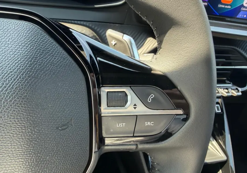 Gros plan sur la partie droite du volant du Peugeot 2008 Hybrid gris, avec commandes audio et téléphone intégrées.