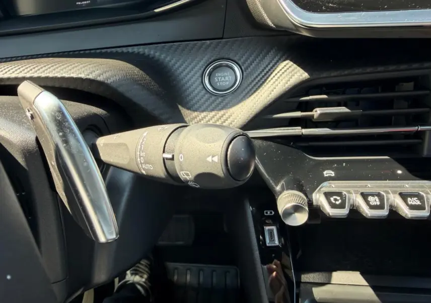 Détail intérieur du tableau de bord du Peugeot 2008 Hybrid 145 e-DCS6 Allure 2025, avec bouton start/stop et commande de clignotants.