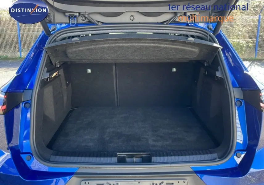 Coffre ouvert vu de l'arrière d'une Renault Symbioz 2025 bleu iron metal, espace de chargement vide et tapis noir.