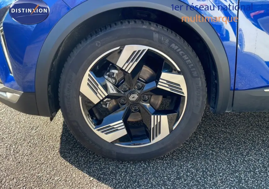 Gros plan sur la roue avant droite de la Renault Symbioz bleu iron metal avec jante noire et argentée au design géométrique.