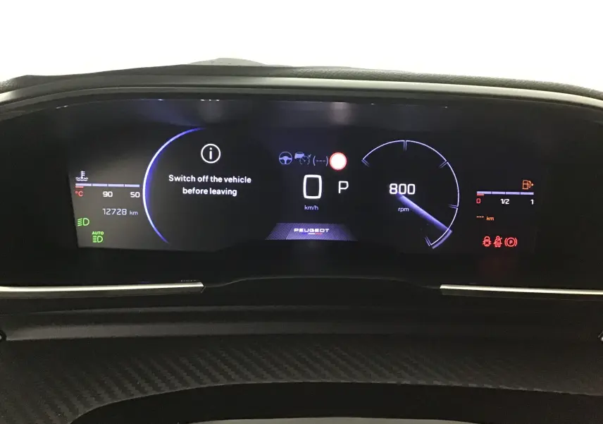 Vue rapprochée du tableau de bord numérique du Peugeot 508 SW gris Artense, affichant la vitesse, le régime et un message d'arrêt.