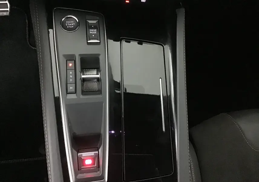 Console centrale noire brillante de la Peugeot 508 SW 2024 avec sélecteur de boîte auto et bouton start/stop.