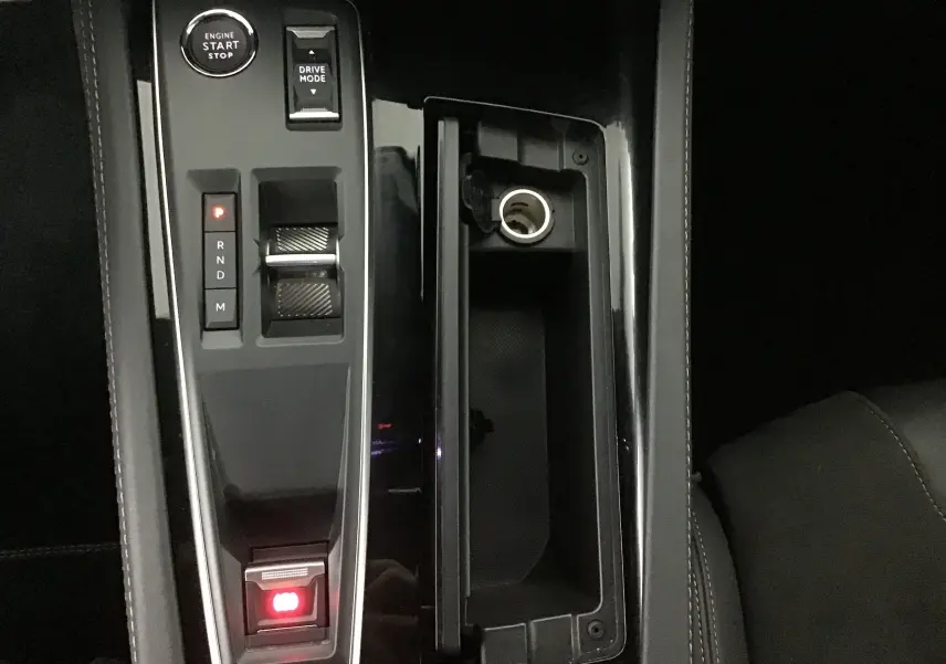 Vue rapprochée de la console centrale noire brillante avec levier de vitesses et bouton start du Peugeot 508 SW gris Artense 2024.