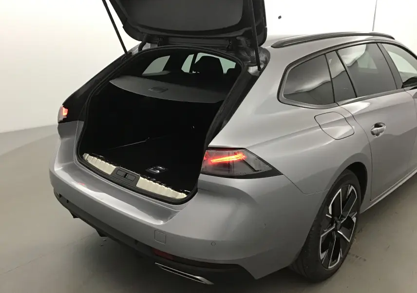 Vue 3/4 arrière droite d'une Peugeot 508 SW gris Artense avec coffre ouvert et feux arrière allumés.