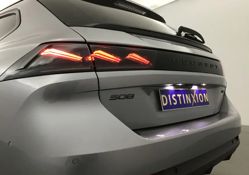 Vue 3/4 arrière droite d'une Peugeot 508 SW gris Artense avec feux arrière LED distinctifs allumés.