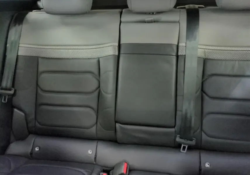 Vue rapprochée des sièges arrière en cuir noir de la Citroën C5 X 2024 avec ceinture de sécurité et accoudoir central rabattable.