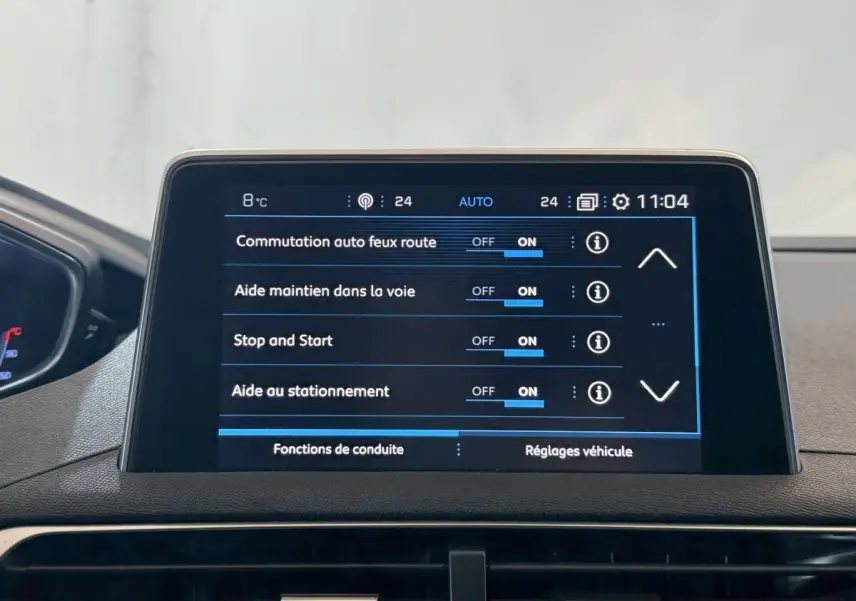 Écran tactile central du tableau de bord du Peugeot 3008 vert, affichant les réglages d'aides à la conduite.