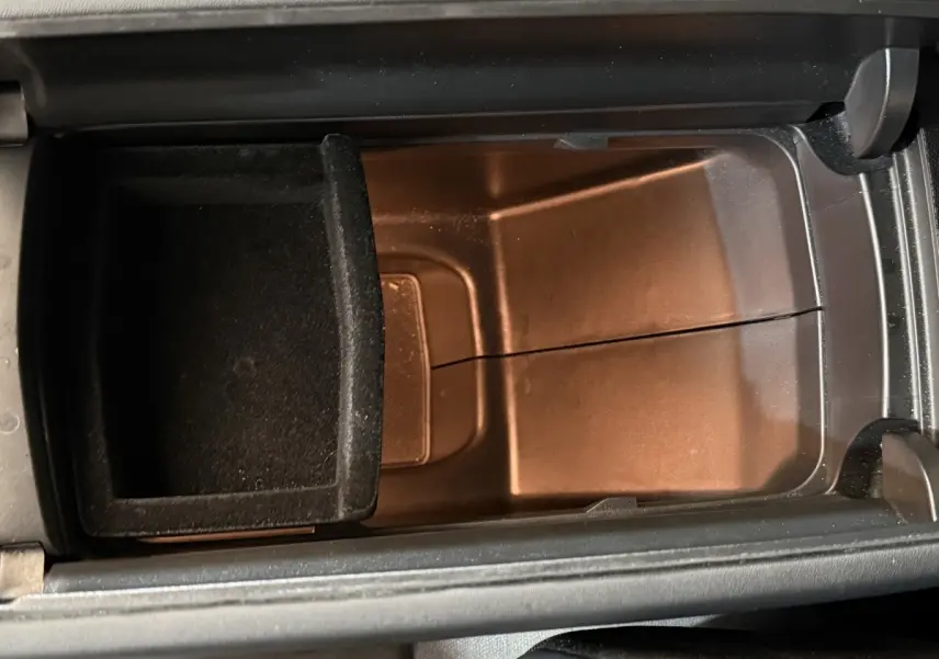 Vue rapprochée de la console centrale ouverte du Peugeot 3008, montrant un compartiment de rangement noir.