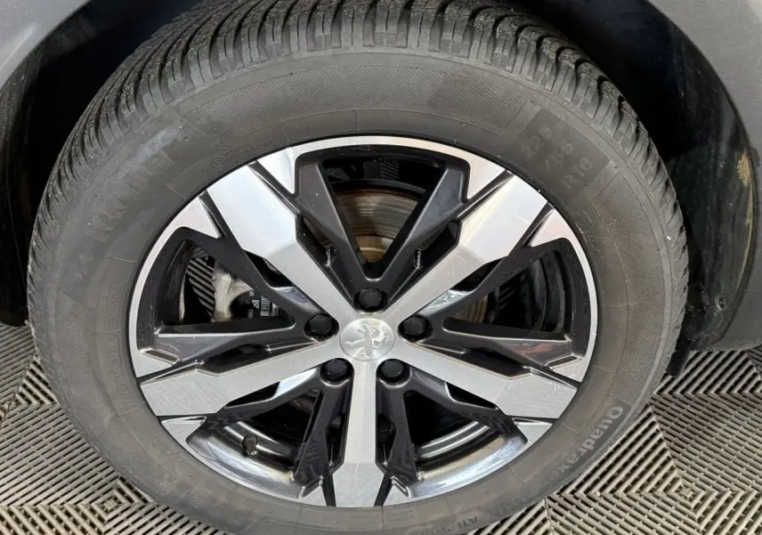 Gros plan sur la roue avant gauche d’un Peugeot 3008 vert, jante alliage bicolore noire et argentée.