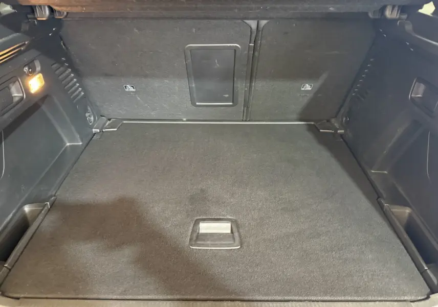 Coffre spacieux du Peugeot 3008 Puretech 130 vert, vue intérieure avec banquette arrière rabattue et éclairage latéral.