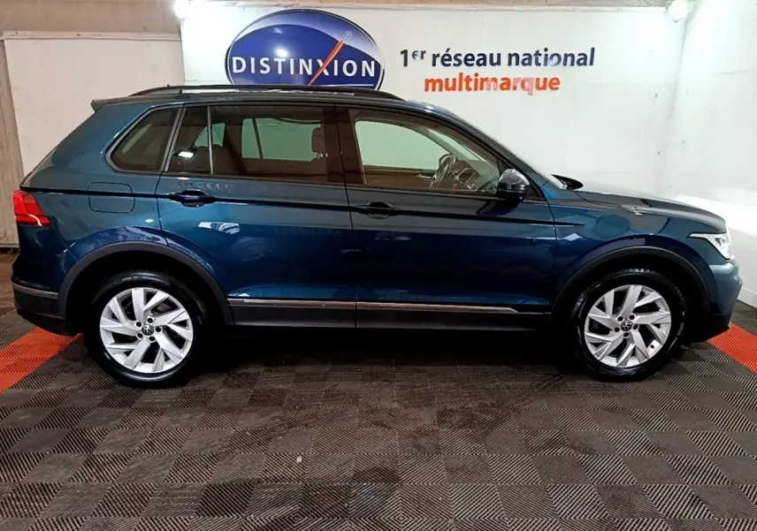 Vue de profil côté gauche d’un Volkswagen Tiguan bleu hybride rechargeable dans un showroom intérieur.