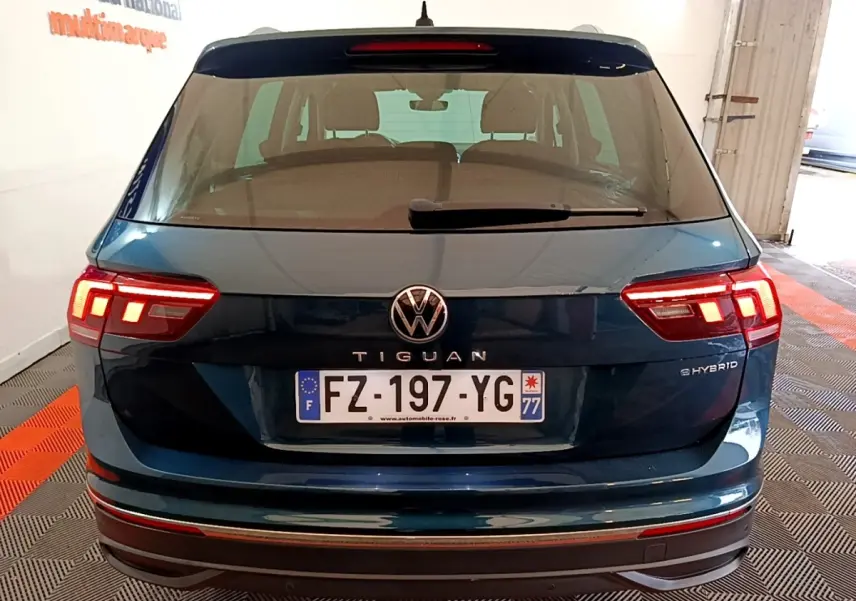 Vue arrière d'un Volkswagen Tiguan bleu hybride rechargeable avec feux LED allumés et plaque d'immatriculation française.