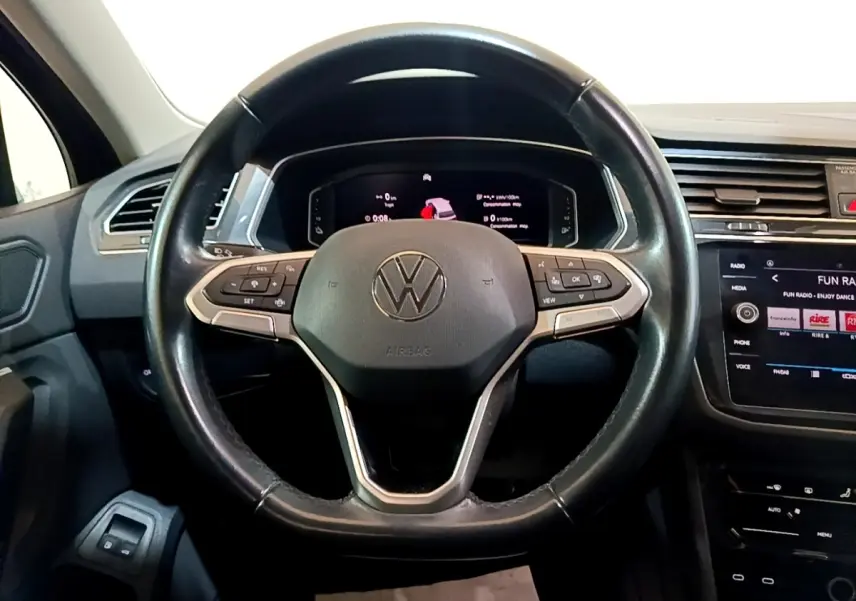 Vue rapprochée du volant cuir multifonctions et tableau de bord numérique du Volkswagen Tiguan bleu hybride rechargeable 2021.