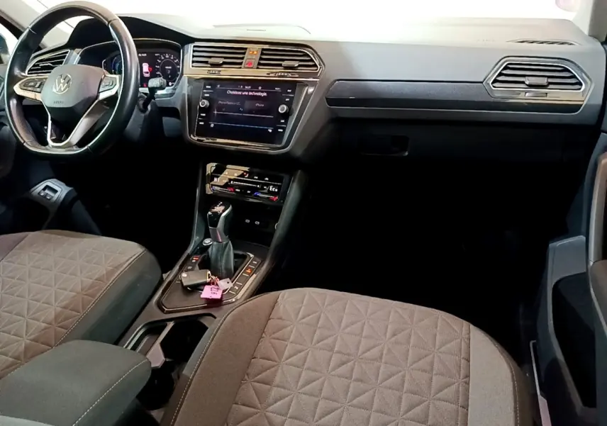 Vue intérieure avant du Volkswagen Tiguan 1.4 eHybrid 2021, sièges gris, tableau de bord avec écran tactile et volant cuir.