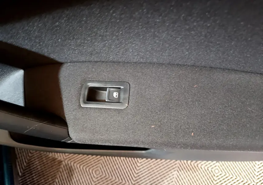 Gros plan sur la commande de verrouillage des portes intégrée dans la garniture noire d'une portière intérieure.