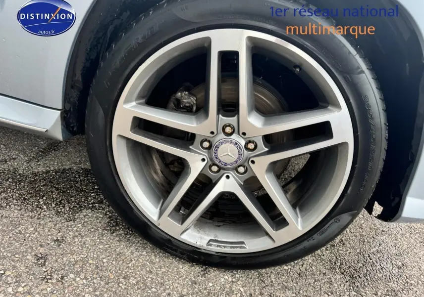 Gros plan sur la jante alu argentée avec logo Mercedes d’un Mercedes GLK noir, roue côté droit.