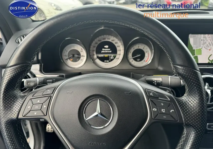 Vue rapprochée du volant cuir multifonction noir d’un Mercedes GLK 350 4matic avec tableau de bord et écran de navigation visible.